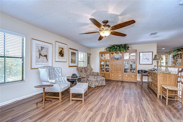 living area featuring ceiling fan, hardwood / wood-style floors, and a textured ceiling