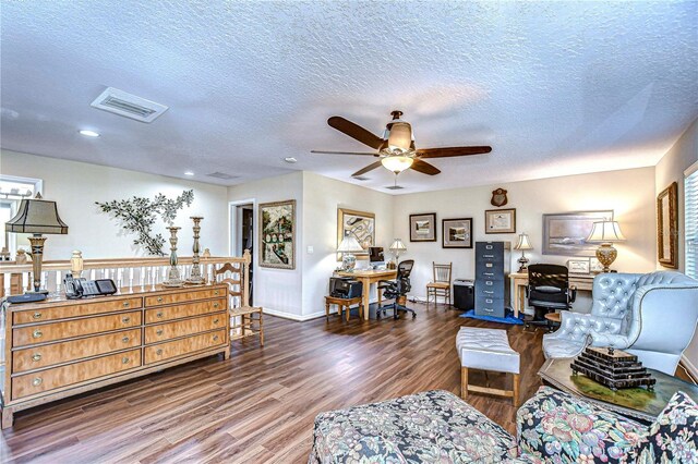 living room with dark hardwood / wood-style floors, ceiling fan, and a textured ceiling