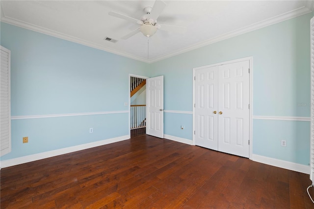 unfurnished bedroom with a closet, ceiling fan, crown molding, and dark wood-type flooring