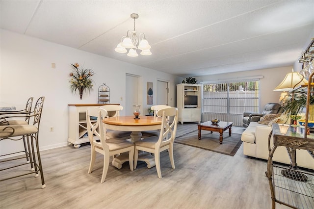 dining space featuring a textured ceiling, light hardwood / wood-style flooring, and a notable chandelier