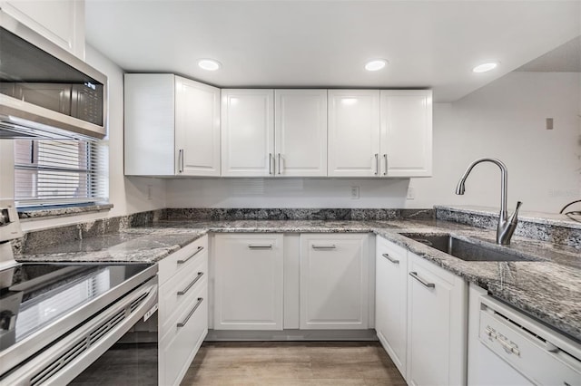 kitchen with white cabinets, light hardwood / wood-style floors, sink, and white dishwasher