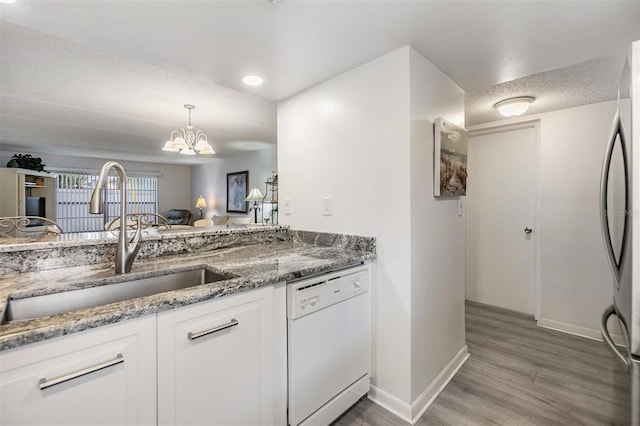 kitchen with dishwasher, sink, a notable chandelier, white cabinetry, and wood-type flooring