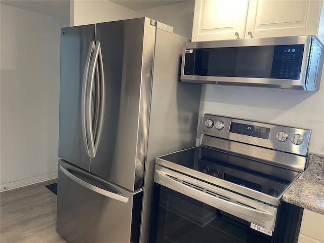 kitchen with wood-type flooring, white cabinetry, and stainless steel appliances