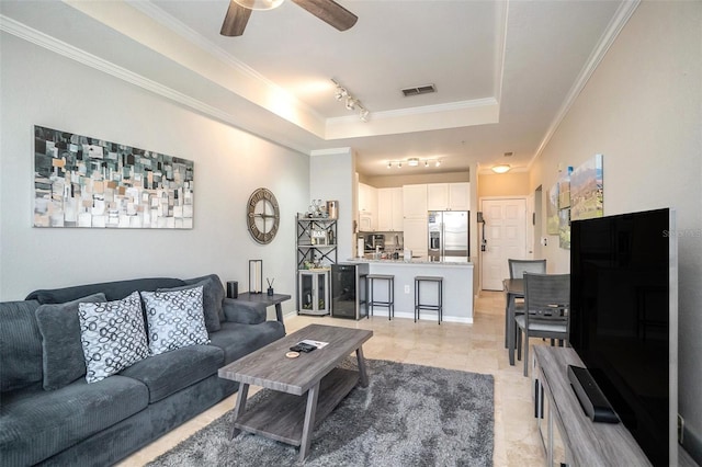 living room featuring track lighting, a raised ceiling, ceiling fan, and ornamental molding