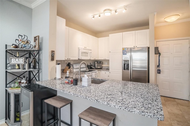 kitchen featuring light stone countertops, white cabinetry, stainless steel appliances, kitchen peninsula, and ornamental molding