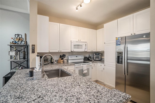 kitchen with white cabinetry, light stone counters, white appliances, and sink