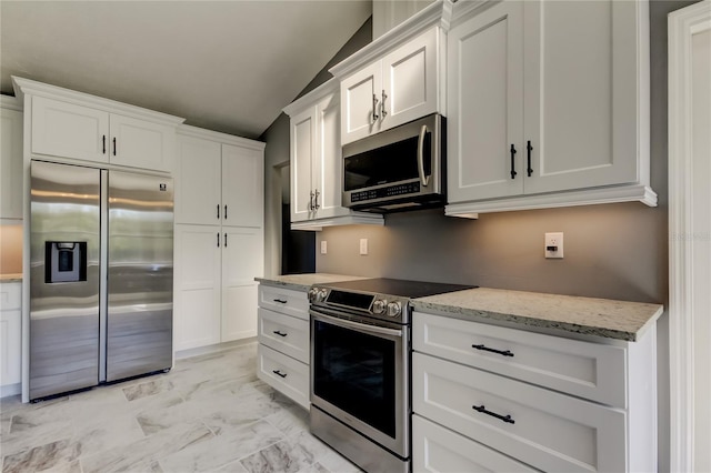 kitchen featuring white cabinets, light stone countertops, stainless steel appliances, and vaulted ceiling