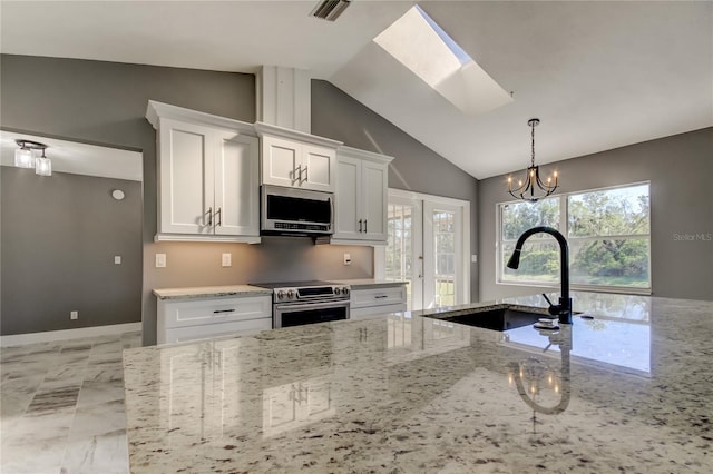 kitchen with lofted ceiling with skylight, white cabinets, sink, appliances with stainless steel finishes, and light stone counters