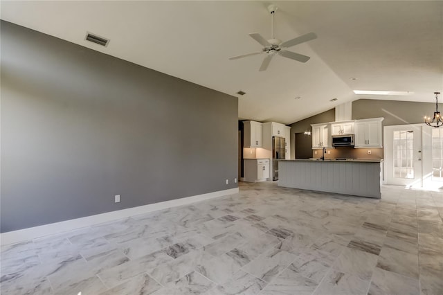 unfurnished living room with ceiling fan with notable chandelier, lofted ceiling, and sink