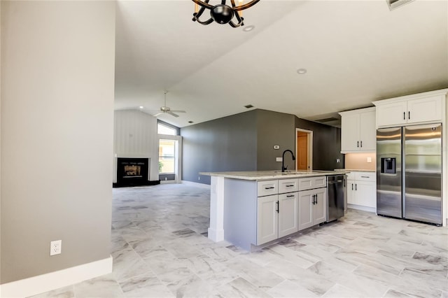 kitchen featuring a large fireplace, white cabinetry, lofted ceiling, and appliances with stainless steel finishes