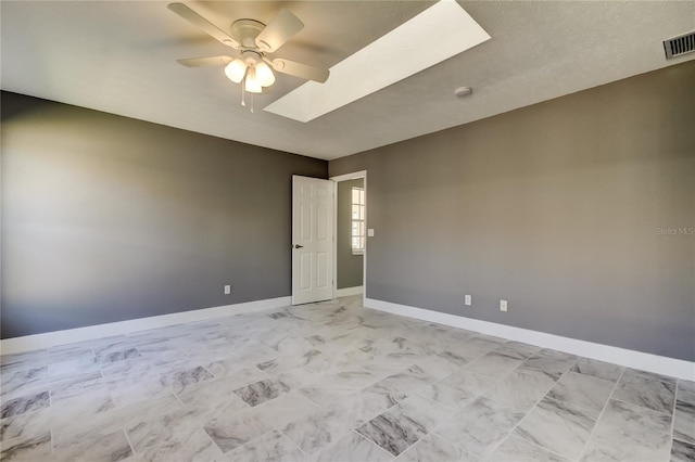 spare room with ceiling fan, a textured ceiling, and a skylight