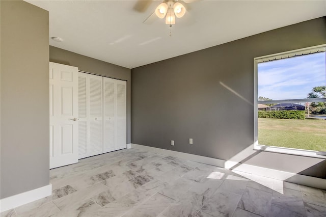 unfurnished bedroom with ceiling fan and a closet