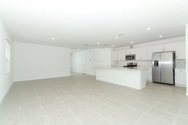 kitchen featuring white cabinetry, sink, stainless steel appliances, an island with sink, and light tile patterned floors