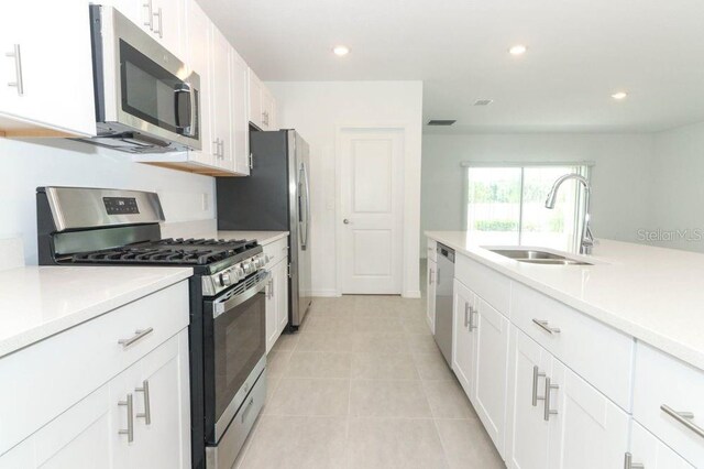 kitchen featuring sink, white cabinets, light tile patterned floors, and appliances with stainless steel finishes