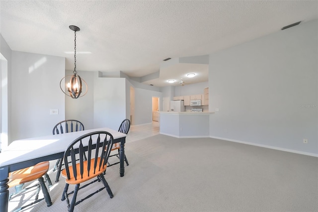 dining room with light colored carpet, a chandelier, and a textured ceiling