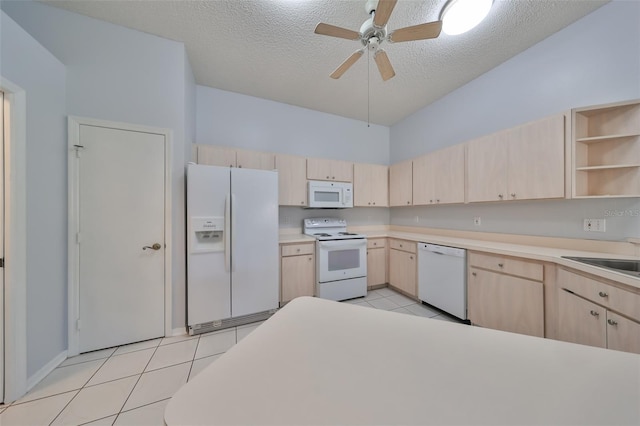 kitchen with light tile patterned floors, white appliances, a textured ceiling, and light brown cabinetry