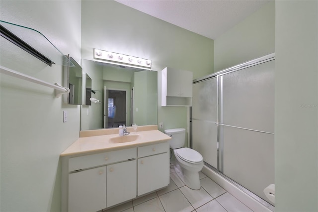 bathroom featuring tile patterned floors, a shower with door, vanity, and toilet