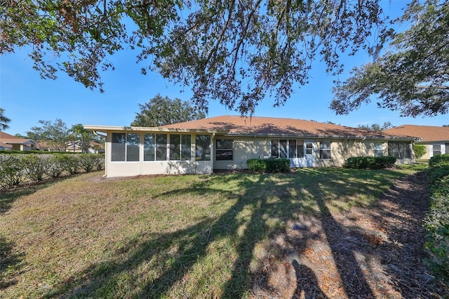 rear view of property with a lawn and a sunroom