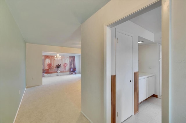 corridor with light carpet and an inviting chandelier