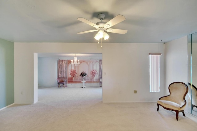 sitting room featuring light colored carpet and ceiling fan with notable chandelier