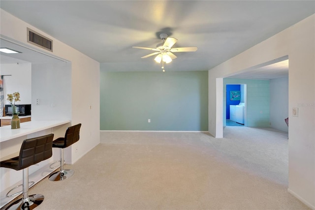 interior space with washing machine and dryer, ceiling fan, light colored carpet, and built in desk