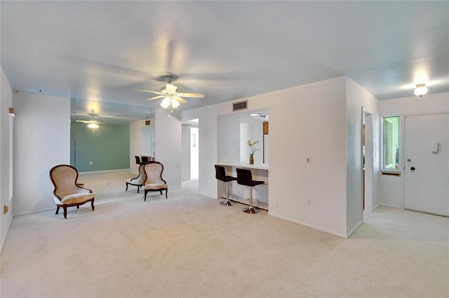 living area with light carpet and ceiling fan