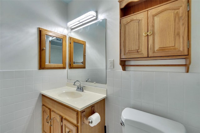 bathroom featuring vanity, toilet, and tile walls