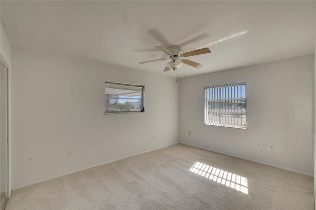 empty room featuring ceiling fan and light carpet