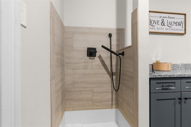 bathroom with tiled shower and vanity