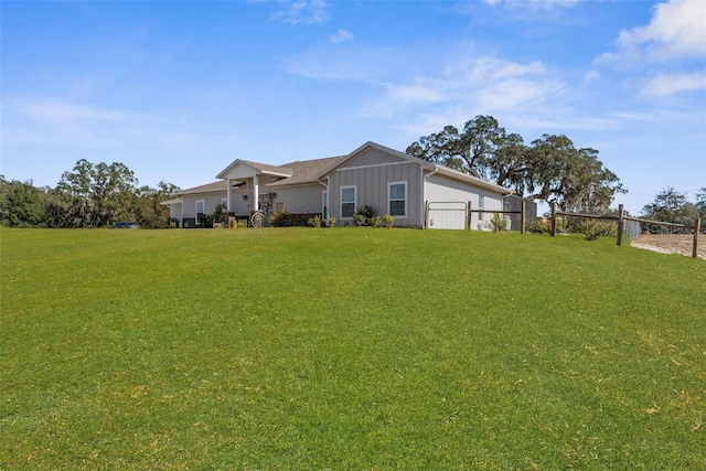 exterior space featuring a front lawn, board and batten siding, and fence