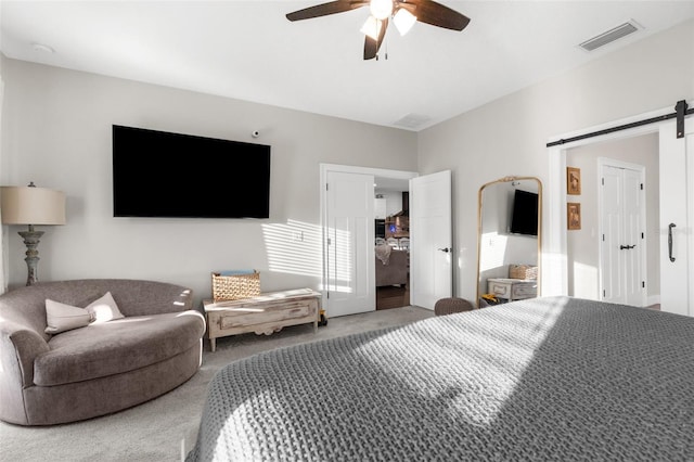 bedroom featuring carpet floors, a barn door, visible vents, and ceiling fan