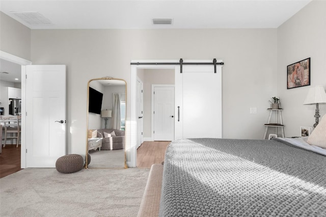 bedroom with light carpet, a barn door, visible vents, and stainless steel fridge with ice dispenser