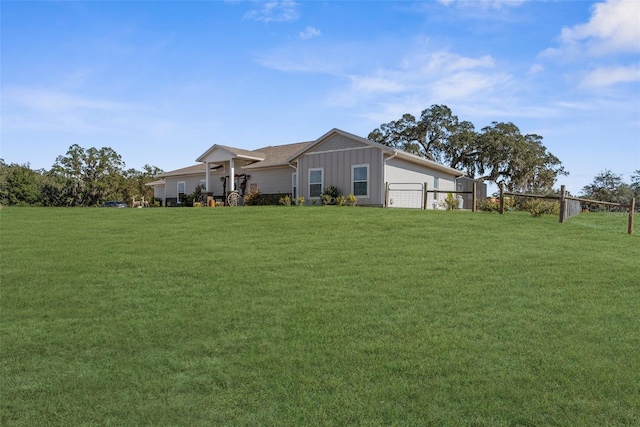 view of front of home with a front lawn, board and batten siding, and fence