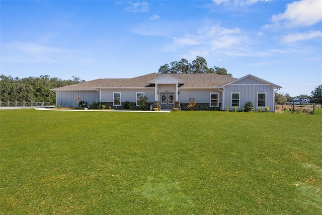 ranch-style house with a front yard, fence, board and batten siding, and french doors