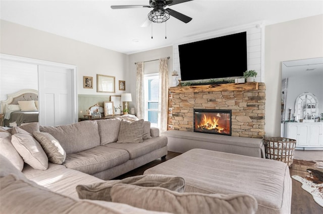 living area featuring a ceiling fan, a fireplace, and wood finished floors