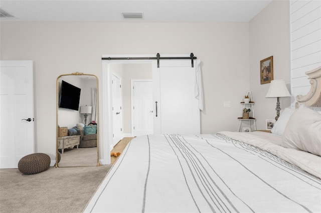 bedroom featuring a barn door, visible vents, and light colored carpet