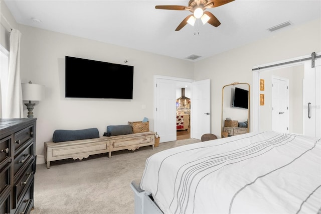 bedroom with light carpet, ceiling fan, a barn door, and visible vents