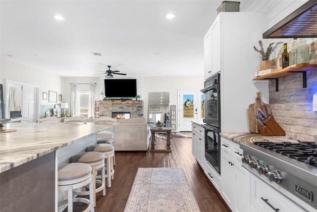 kitchen featuring a healthy amount of sunlight, stainless steel gas cooktop, a fireplace, and a breakfast bar area