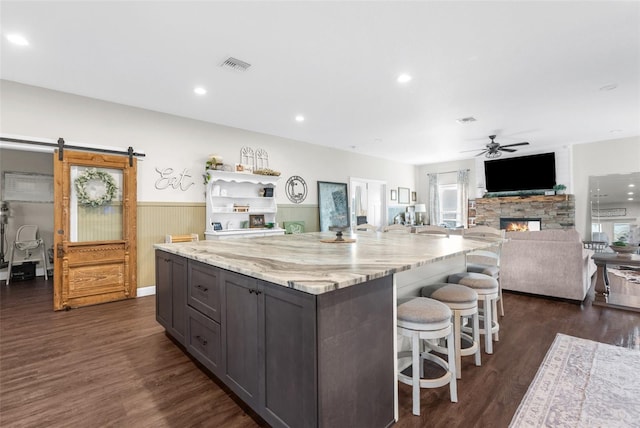 kitchen featuring a ceiling fan, a wainscoted wall, dark wood finished floors, and a barn door