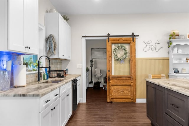 kitchen featuring a wainscoted wall, a sink, white cabinets, and light stone countertops