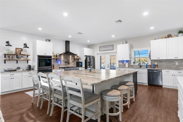 kitchen with visible vents, wall chimney exhaust hood, dark wood-style flooring, stainless steel appliances, and french doors