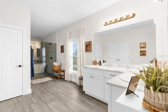 full bathroom featuring wood finished floors, a shower stall, and vanity