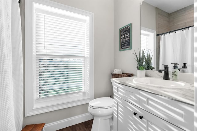 bathroom featuring wood finished floors, vanity, toilet, and baseboards