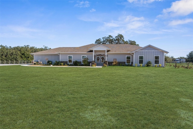 ranch-style house with board and batten siding, a front yard, french doors, and fence