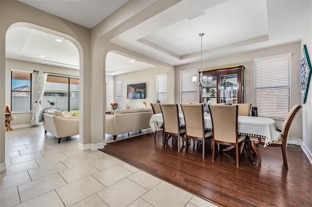 dining space featuring a tray ceiling, light hardwood / wood-style flooring, and an inviting chandelier