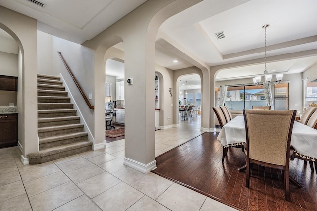 dining room featuring a notable chandelier, light hardwood / wood-style floors, and a tray ceiling