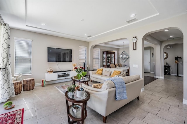 tiled living room with a chandelier and a tray ceiling