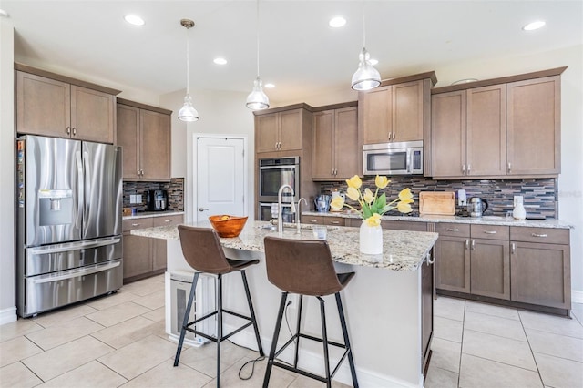 kitchen with a center island with sink, decorative light fixtures, sink, and appliances with stainless steel finishes