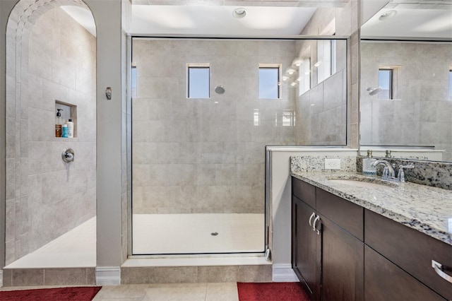 bathroom featuring tile patterned flooring, vanity, and tiled shower