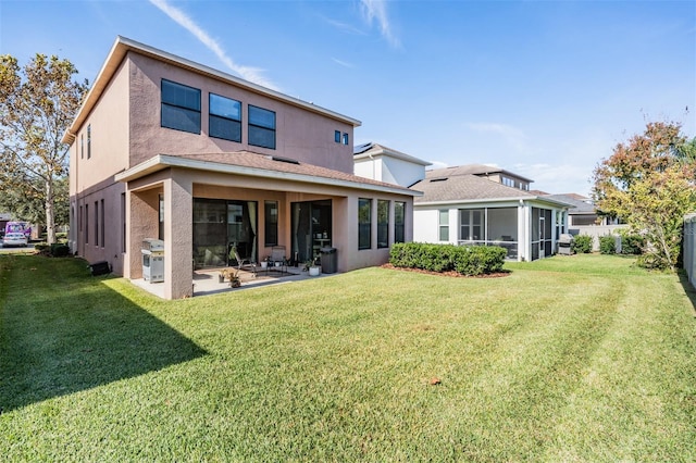 rear view of house with a lawn, a patio area, and a sunroom